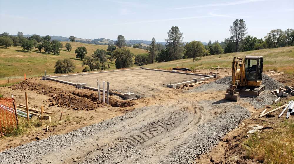 Graded home site with foundation and utility hookups prepared for a manufactured home